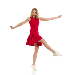 Fototapeta premium Carefree Beautiful Young Woman In Red Mini Dress And Sneakers Is Dancing