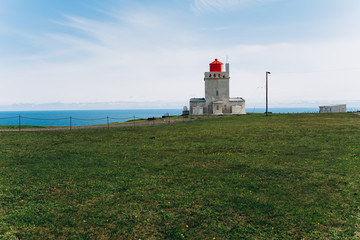Fototapeta na wymiar White lighthouse on the shore of the ocean. Lighthouse in Iceland.