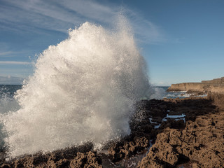 Fototapeta na wymiar Wave hits the coast creating huge splash, Sunny day, county Clare, Ireland.