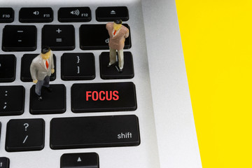 FOCUS inscription written words, laptop and businessman miniature. Business and technology concept