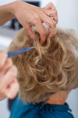 Fototapeta premium Hands of hairdresser making hairstyle for female