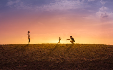 Happy family playing outdoors at sunset.