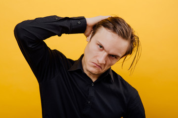 man looks with disgust at the camera, isolated yellow background, black shirt, copy space
