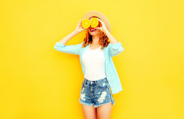 Summer portrait happy smiling woman holding in her hands slices of orange hiding her eyes in straw...