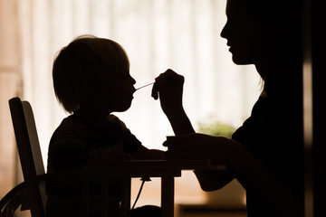 mother feeding her toddler spoon of food