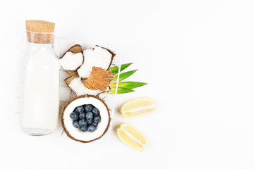 Coconut vegan milk in a bottle and coconuts on white background