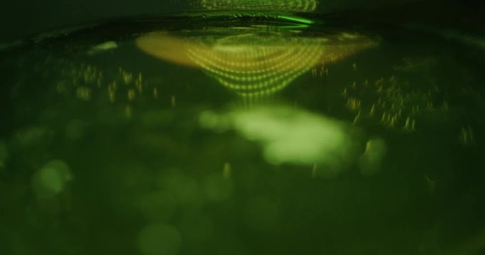 POV slow motion macro of fresh foamy beer going out from the uncorked green bottle. Shot in 8K.