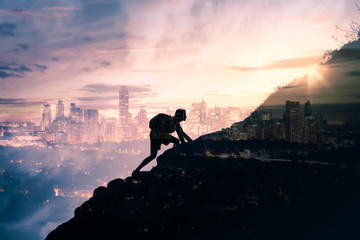 Fototapeta silhouette of man climbing up mountain overlooking city obraz
