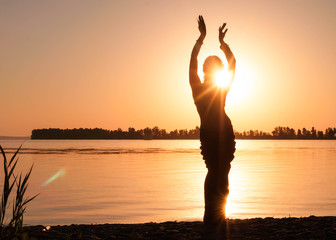 silhouette of dancing woman tradition trible oriental near big river coast at dawn