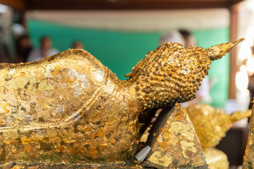 Gold leaf placed on a statue of Buddha by worshipers at the Wat Arun temple in Bangkok, Thailand.