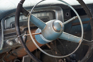 Old rusty and damaged antique car wreck in very poor condition on house yard.
