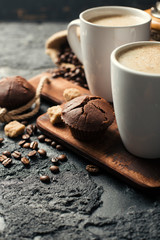 Black fried coffee beans in cafe with cookie and cake on dark textured background
