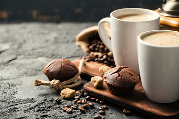 Black fried coffee beans in cafe with cookie and cake on dark textured background