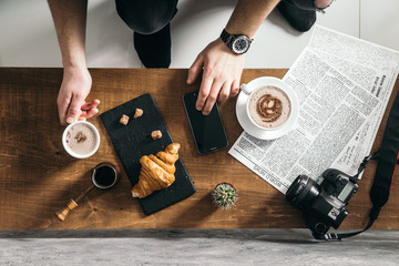 Young man in morning cafe drink coffee and read daily news