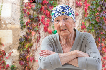 Portrait of mature woman recovering after chemotherapy and looking at camera while sitting outside...