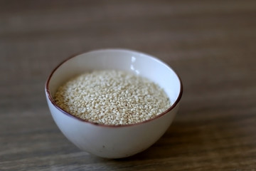 Small bowl of sesame on a wooden table. Selective focus.