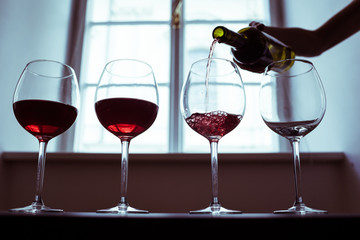 hand poring glass of red wine, wine tasting 