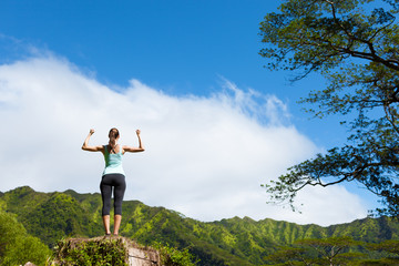 strong young woman flexing on top of mountain