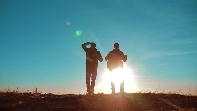 teamwork. two tourists hikers men and dog with backpacks at sunset go hiking trip. slow motion video. journey and hikers the dog go walking. travel mountains silhouette. hikers adventure and the dog