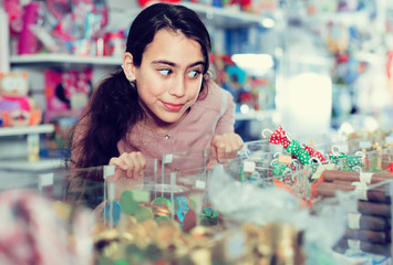 glad schoolgirl delighted with choosing lollipop in store