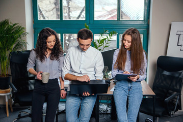 Fototapeta premium Business team of young architects or designers creating new project while working in the modern stylish office with big window on background.