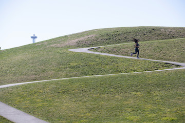 Beautiful woman with long black hair wearing yoga pants and sports bra outside during park workout