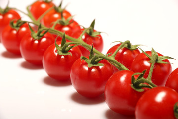 Ripe fresh Juicy organic cherry tomatoes closeup on branch isolated on a white background.