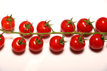 Ripe fresh Juicy organic cherry tomatoes closeup on branch isolated on a white background.