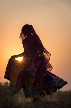 Woman dancing in front of the sun, Pushkar, Rajasthan, India, Asia