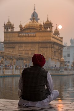 Sikh man watching the sunrise over the Golden Temple, Amritsar, Punjab, India, Asia