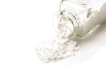 Closeup of an apothecary bottle on its side with a white powder spilling out.