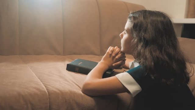 Little girl praying in the night. Little girl hand praying. little girl holy bible prays lifestyle with bible in her hands. the catholicism sacred holy bible. children and religion upbringing faith