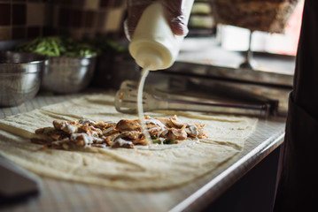 cook chapati. Preparation of traditional shawarma and shawarma (doner kebab). A man pours sauce on...