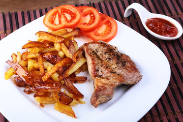 Grilled free-range beef steak with potato free, fresh tomatoes and sauce on a brown stone background