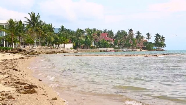Tropical island with sandy beach and dea waves in windy weather