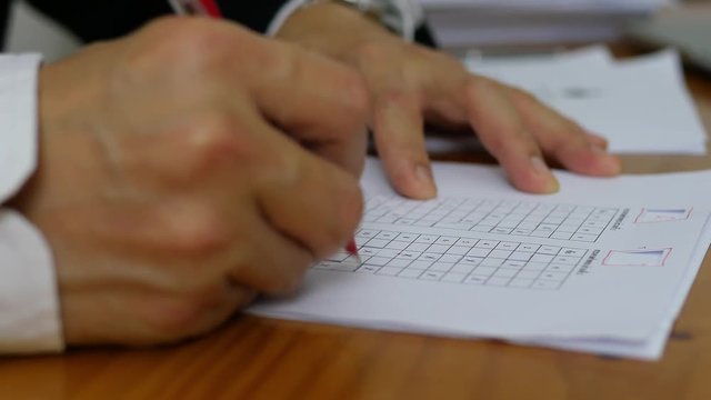 Teacher is checking multiple choices examination answer sheet - education activity concept