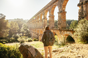 Backpacker astonished by ancient monument. Roman Aqueduct Pont del Diable in Tarragona, Spain