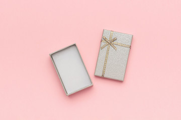 Open gray gift box with bow on pink pastel background in minimal style. Top view Copy space Mockup