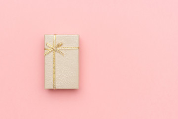 Beige gift box with bow on pink pastel background in minimal style. Top view Copy space Mockup