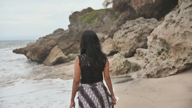 Indonesian girl posing on a beautiful and rocky beach in Bali. Idonezia.