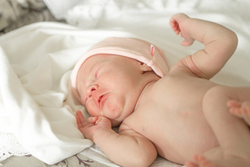 Newborn naked baby crying on the bed