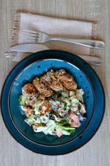 Fried chicken with sesame and zucchini and carrot salad with yoghurt sauce. Top view.