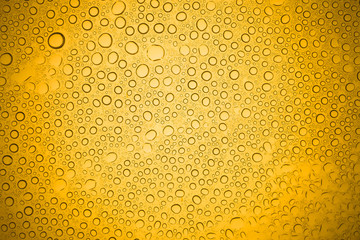 Water drops on yellow glass, Rain droplets on glass background.