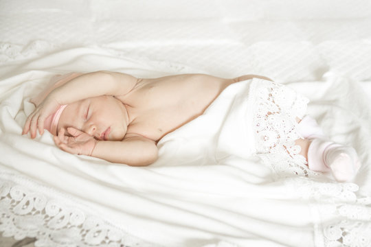 sleeping naked newborn baby girl on a white blanket