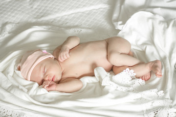 sleeping naked newborn baby girl on a white blanket