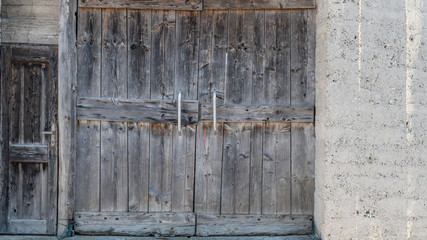 old wooden door small and big on a concrete wall