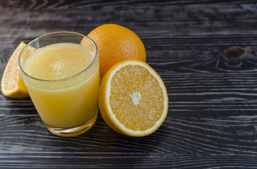 Orange juice and oranges on a dark background