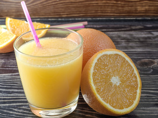 Orange juice and oranges on a dark background