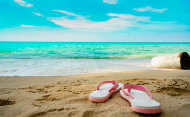 Pink and white sandals on sand beach. Casual style flip-flop were removed at seaside. Summer...