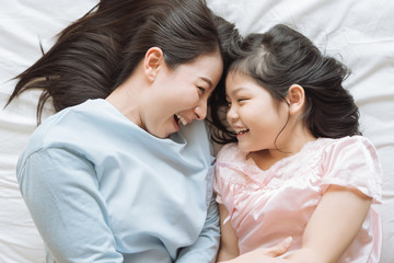 Mother and her daughter child girl playing in the bedroom .Happy Asian family